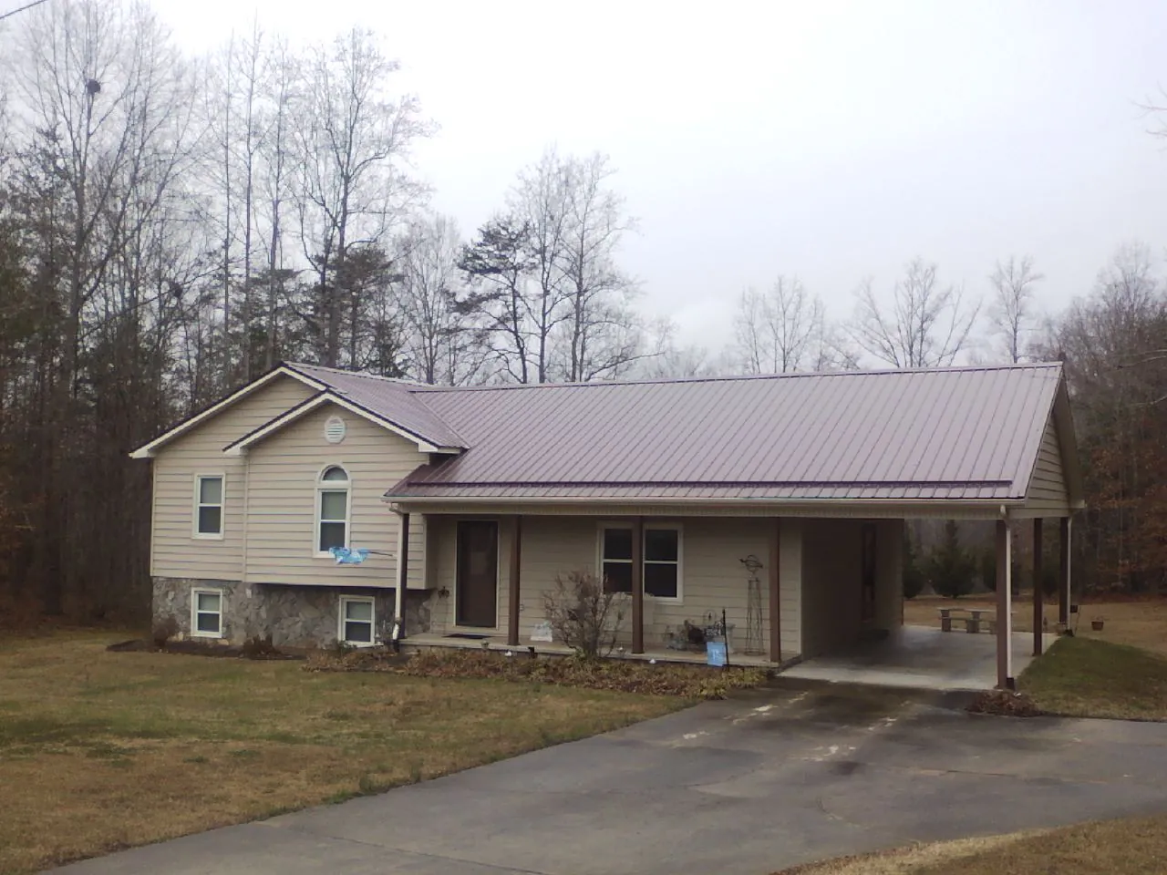 Burgundy metal roof on a tan split level home with an attached carport in Stevensville