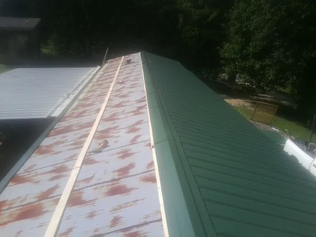 Old rusted panels beside newly installed green metal roofing — Wind Damage Roof Repair by Roofing Brothers in Stevensville
